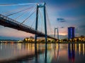 Suspension bridge bridge across the river at night. Night illumination of buildings, reflections