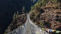 Suspension bridge with colorful flags flying in the wind, on top of a mountain range Royalty Free Stock Photo