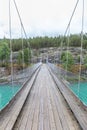 Suspension bridge over mountain river with clear turquoise water. Hiking in Norway. Mountain river with a pedestrian bridge. The Royalty Free Stock Photo