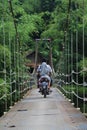 Suspension bridge over the river with motorcycle crossing on it in the morning in Sukabumi, west java, Indonesia. traditional