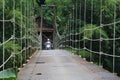 Suspension bridge over the river with motorcycle crossing on it in the morning in Sukabumi, west java, Indonesia. traditional