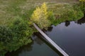 Suspension bridge over a small river, aerial view. Hanging bridge across water. Summer landscape