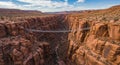 Suspension bridge spans a dramatic red rock canyon with steep, rugged cliffs. The Royalty Free Stock Photo