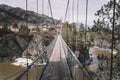 Suspension hanging bridge above water mountain river stream covered with ice snow on the background of rock island Royalty Free Stock Photo