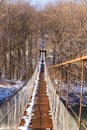 Suspention bridge over the mountain river winter view. Royalty Free Stock Photo