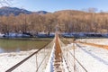 Suspention bridge over the mountain river winter view. Royalty Free Stock Photo