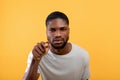 Suspicion concept. African american man gazing and pointing finger at camera, standig over yellow background Royalty Free Stock Photo