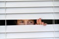 Suspicious adult woman looking outside home window Royalty Free Stock Photo