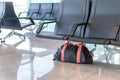 Suspicious black and red bag left unattended under chair on platform at train station or airportl. Terrorism and public safety