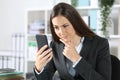 Suspicious executive checking smart phone at office Royalty Free Stock Photo