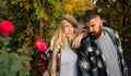 Suspicious looking at camera couple of hipsters. Young bearded man and woman at fall autumnal background and beautiful