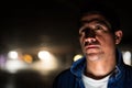 Suspicious-looking Hispanic man thinking in dark parking lot Royalty Free Stock Photo