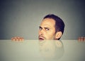 Suspicious man peeking from under table Royalty Free Stock Photo