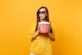 Suspicious puzzled young girl in 3d imax glasses watching movie film looking aside holding bucket of popcorn isolated on