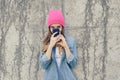 Suspicious or shy woman in casual clothes and pink hat hiding her face behind smartphone, she read secter information. The woman i Royalty Free Stock Photo