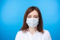 Suspicious woman in aseptic mask. light blue background