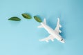Sustainable Aviation Fuel. White airplane model, fresh green leaves on blue background. Green Biofuel for aviation Royalty Free Stock Photo