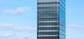 Sustainable modern glass building against a blue sky with clouds.