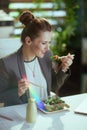 smiling bookkeeper woman in green office eating salad