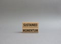 Sustained momentum symbol. Wooden blocks with words Sustained momentum. Beautiful grey background. Business and Sustained momentum