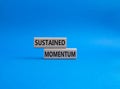 Sustained momentum symbol. Wooden blocks with words Sustained momentum. Beautiful blue background. Business and Sustained momentum