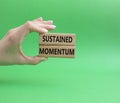 Sustained momentum symbol. Wooden blocks with words Sustained momentum. Beautiful green background. Businessman hand. Business and