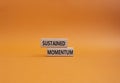 Sustained momentum symbol. Wooden blocks with words Sustained momentum. Beautiful orange background. Business and Sustained