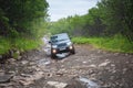 Suv car driving on a dirt off road with puddles and stones in the forest Royalty Free Stock Photo