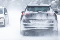 SUV car driving on snowy slippery road inside the forest, having registration number insivisible due to snow Royalty Free Stock Photo