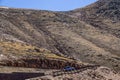 An SUV and a motorcycle take a switchback on a winding mountain road above the tree line - you can see where the road continues on