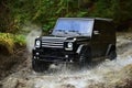 SUV or offroad car in black color crossing water stream Car racing with creek on way. Offroad race in forest Extreme Royalty Free Stock Photo