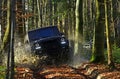 SUV or offroad car on path covered with leaves crossing puddle with water splash. Offroad race on fall nature background Royalty Free Stock Photo