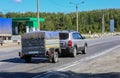 SUV with a trailer moves along a suburban highway Royalty Free Stock Photo