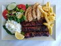 Suvlaki, a traditional Greek dish with fries, salad and tzatziki sauce Royalty Free Stock Photo