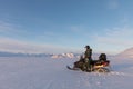 Svalbard, Norway - March 2019: Man standing next to a Yamaha snowmobile in arctic landscape at Svalbard