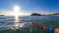 Sveti Stefan - Man bathing in crystal clear water at sand beach next to idyllic island Sveti Stefan, Budva Riviera, Montenegro