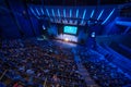 Business crowd attending international seminar in large blue illuminated auditorium