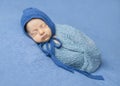 Swaddled newborn sleeping with hood on his head