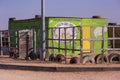 Daycare center in dilapidated green building surrounded by fence with holes located in a township