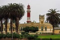 Swakopmund, Namibia - Jul 12, 2019: Red lighthouse, white German fort and row of palms in Swakopmund, Namibia Royalty Free Stock Photo