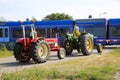 View on two vintage tractors waiting at closed railway crossing barriers
