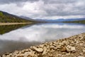 Swamp landscape with reflections in the water of the mountains and shore with large rustic stones