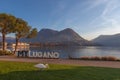 Swan on a meadow in front of metal inscription with the name of city of Lugano