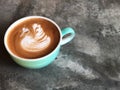 Swan shape latte art coffee in white and green cup on cement floor with natural light Royalty Free Stock Photo