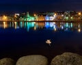 Two swans and the old city of Reykjavik in the reflection of the Tjornin pond