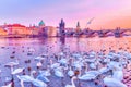 Swans on Vltava river, towers and Charles Bridge at sunset, Prague, Czech Republic.