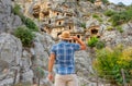 Swarthy caucasian european guy in plaid shirt and a hat stands back and looks in surprise at the ancient unique famous places