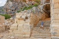 Swarthy caucasian european guy rises in surprise, points to ancient unique famous places in Turkey, Antalya Ancient lycian rock