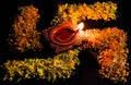 Swastik made with flower petals and clay lamp glowing on it against black background. faith and belief concept