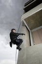 SWAT Team Officer Rappelling and Aiming Gun